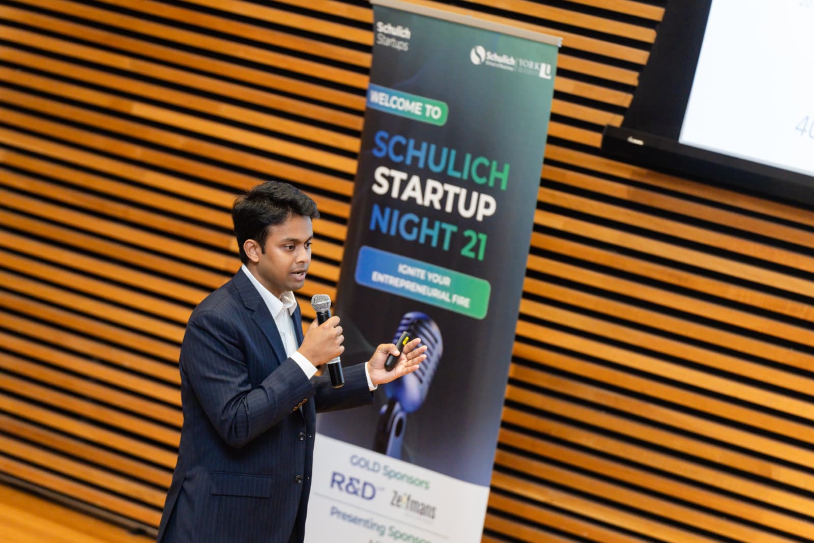 Tamzid Azad speaking with a microphone at Schulich Startup Night